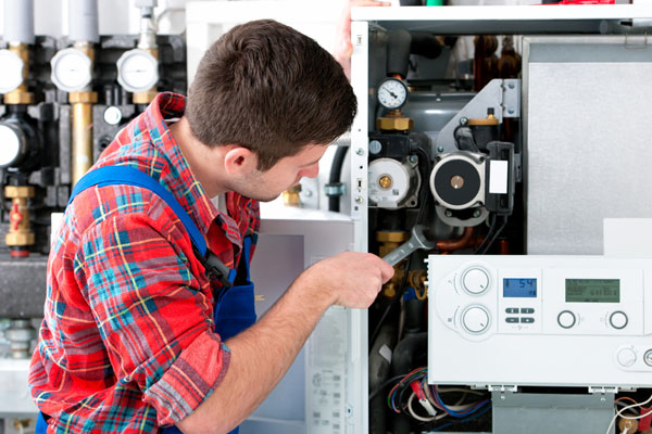 HVAC technician inspecting and repairing boiler controls in Frederick