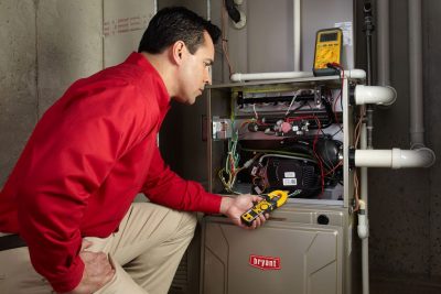 furnace repair Heating and air conditioning technician servicing an indoor furnace in Frederick, CO